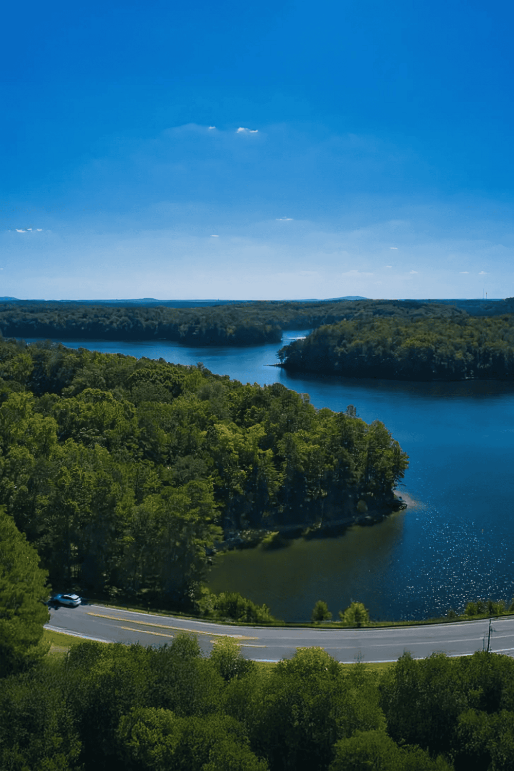Serene river landscape with lush green trees under a bright blue sky, ideal for outdoor adventures and nature exploration.