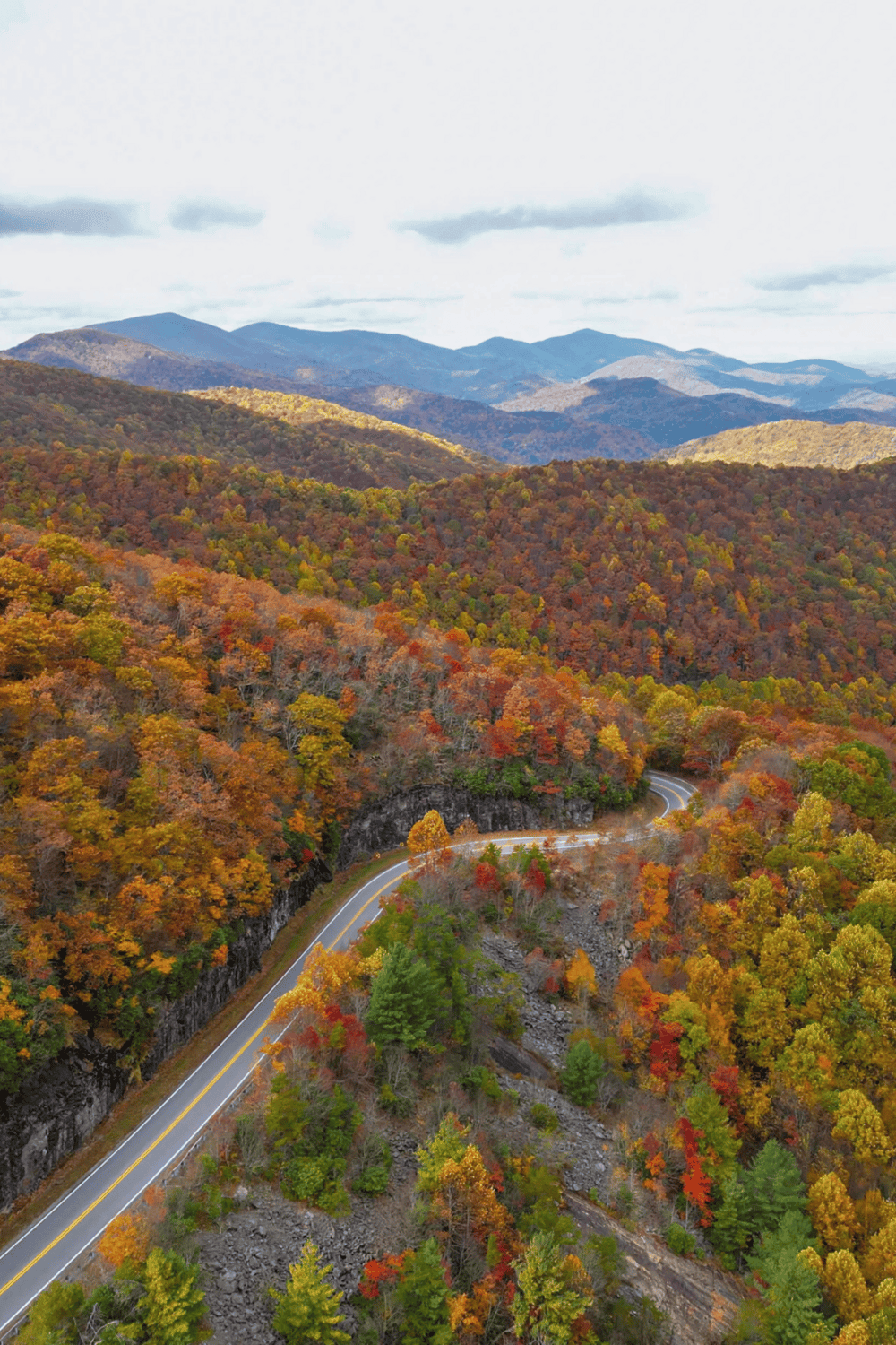 Vibrant autumn mountain landscape with winding road in colorful fall foliage.