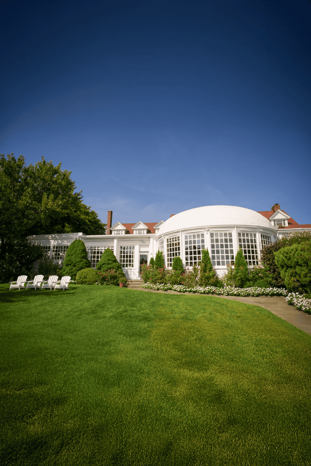1. Elegant white house with lush green lawn and garden under a clear blue sky.