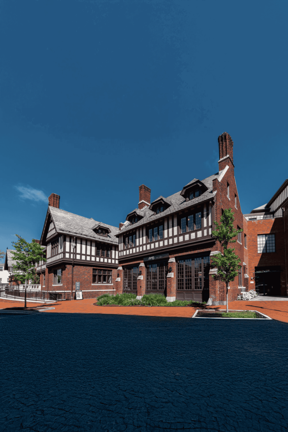 Historic Tudor-style building with brick and timber exterior, bright blue sky in the background.