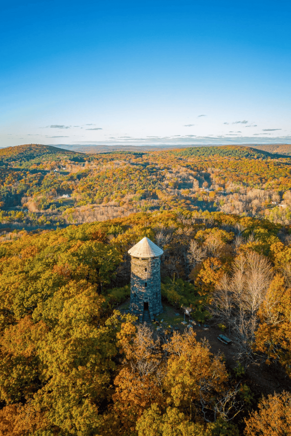 Stone tower amidst colorful autumn forest scenery in scenic mountain landscape.