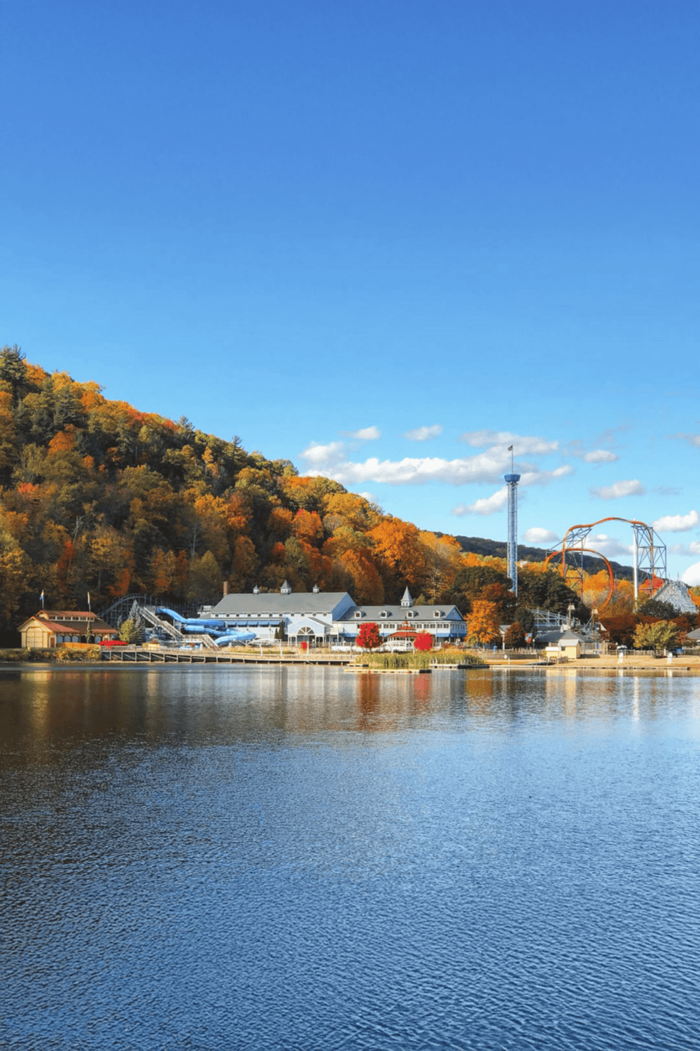 Colorful fall foliage and amusement park near a lake, scenic outdoor destination for family fun.