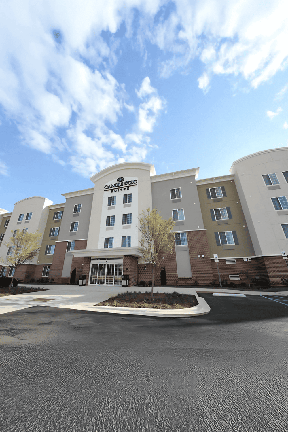 Modern Candlewood Suites hotel exterior with clear sky, dedicated parking, and landscaped grounds.