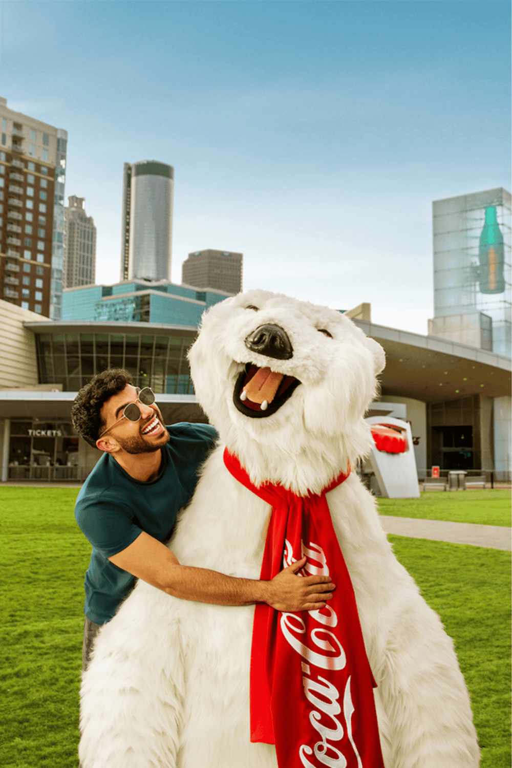 Happy man hugging giant Coca-Cola polar bear mascot in city park for QuestForDirections SEO.