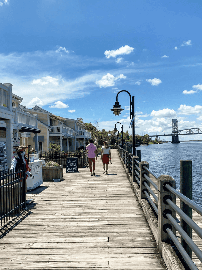 Overwater pier with friendly walkers, scenic waterfront, and bridge view, perfect for exploring waterfront neighborhoods and outdoor activities.