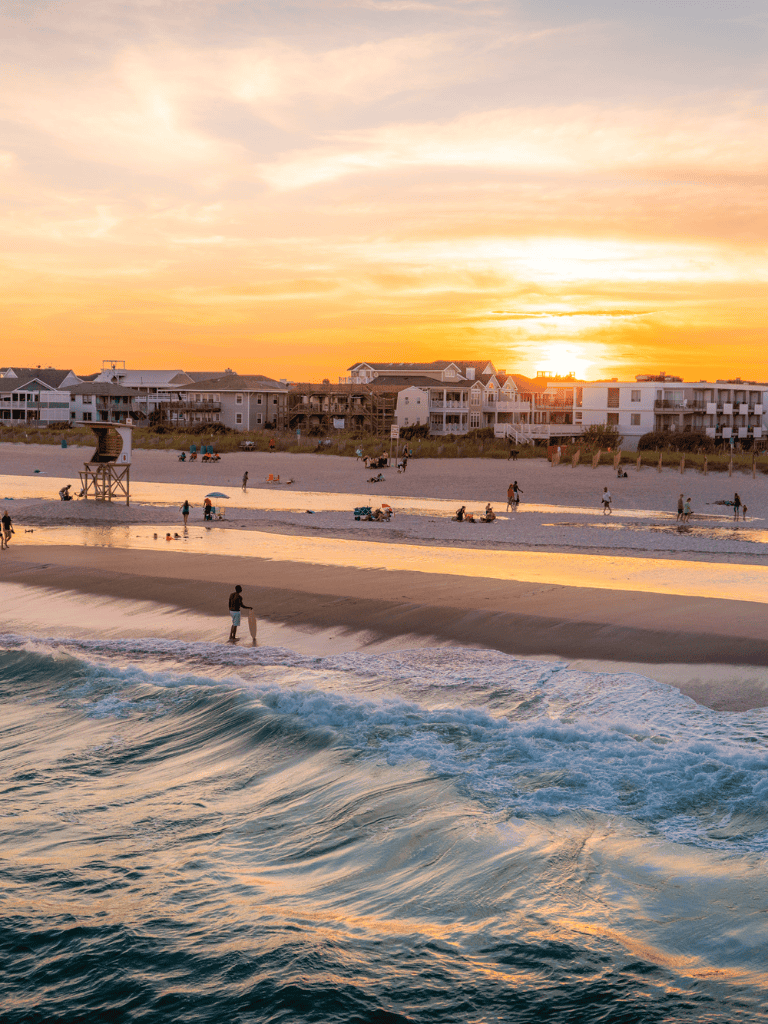 Sunset beach scene with hotels and people relaxing by the ocean at QuestForDirections.