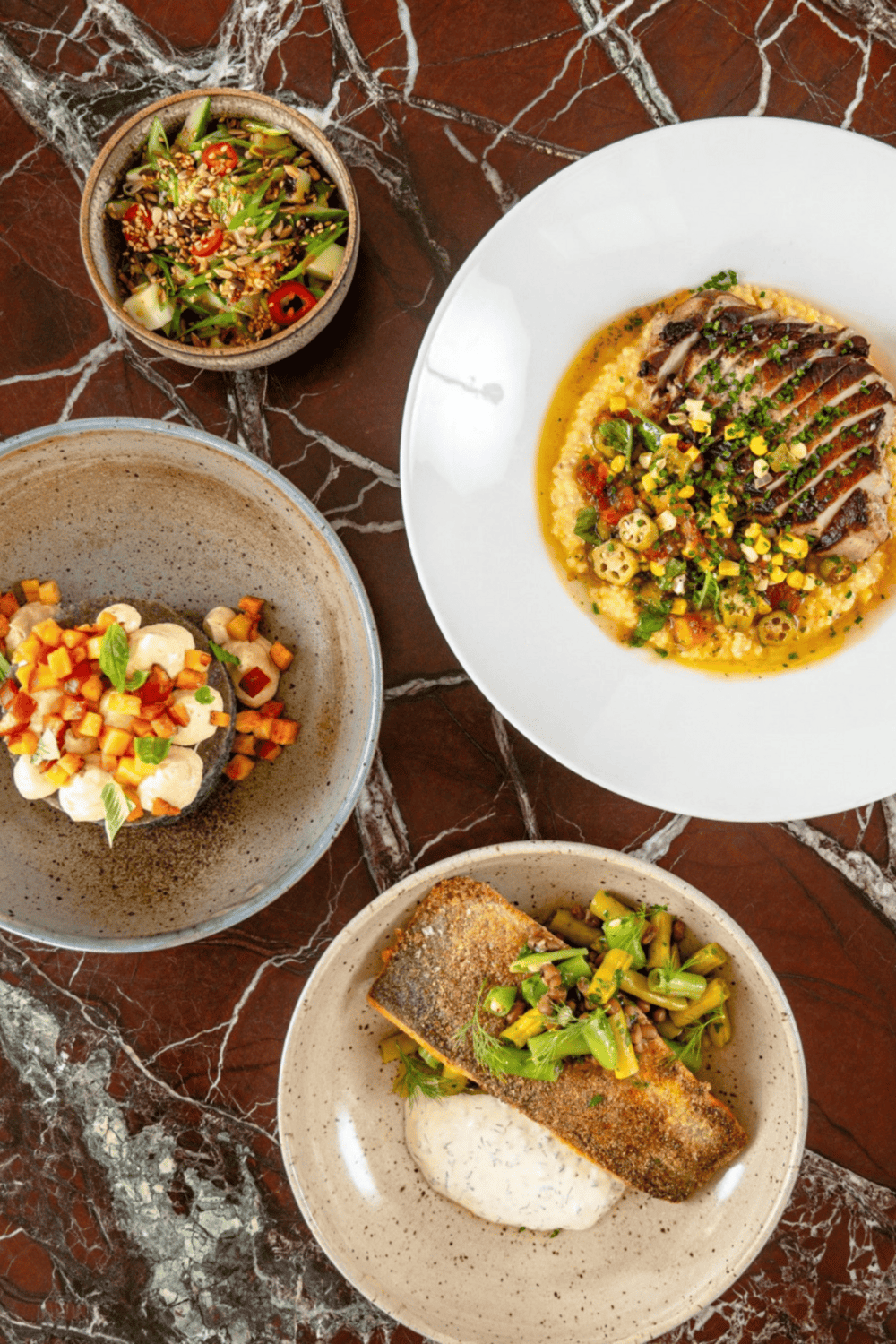 Creamy, flavorful fish dish with vegetables and sauce, served with gourmet sides on a rustic table.