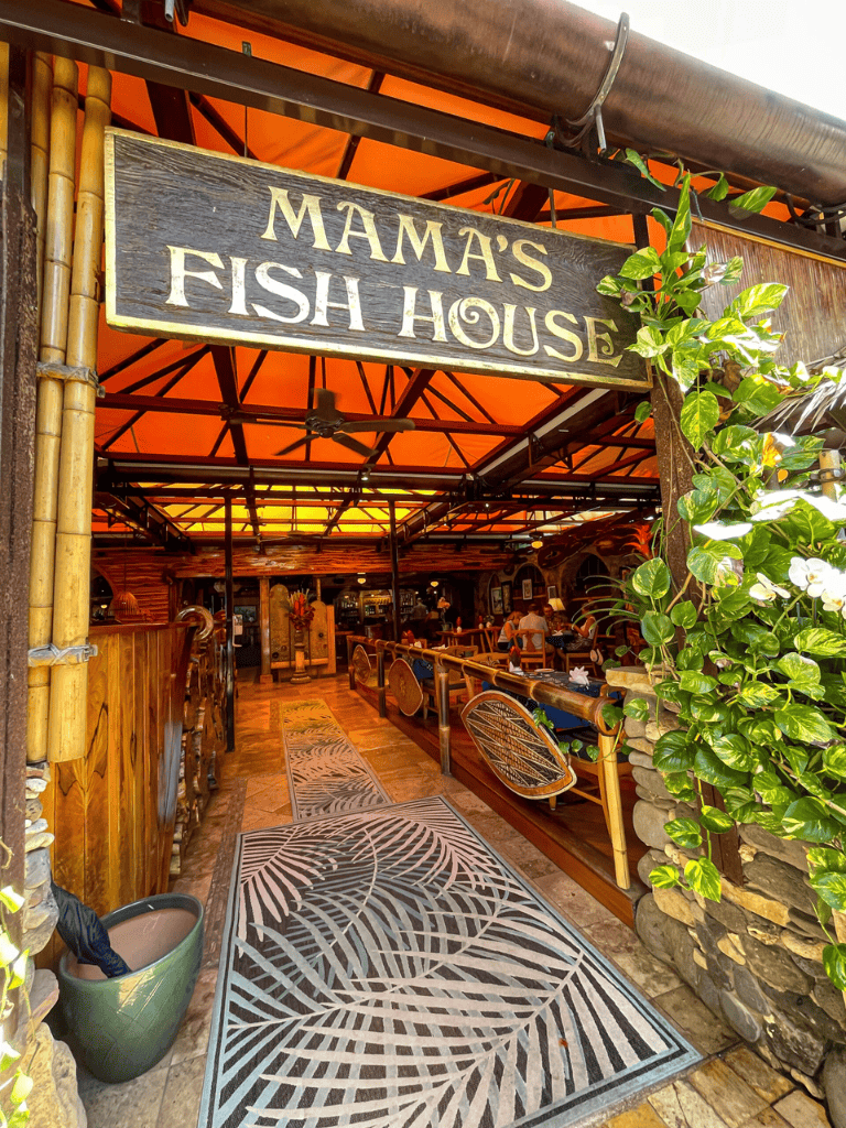 Colorful tropical-themed entrance to Mama's Fish House restaurant with lush greenery and wooden decor.