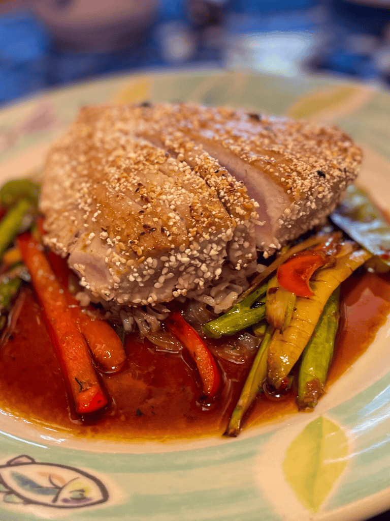 Grilled herb-crusted chicken with roasted vegetables and savory sauce for a hearty meal.