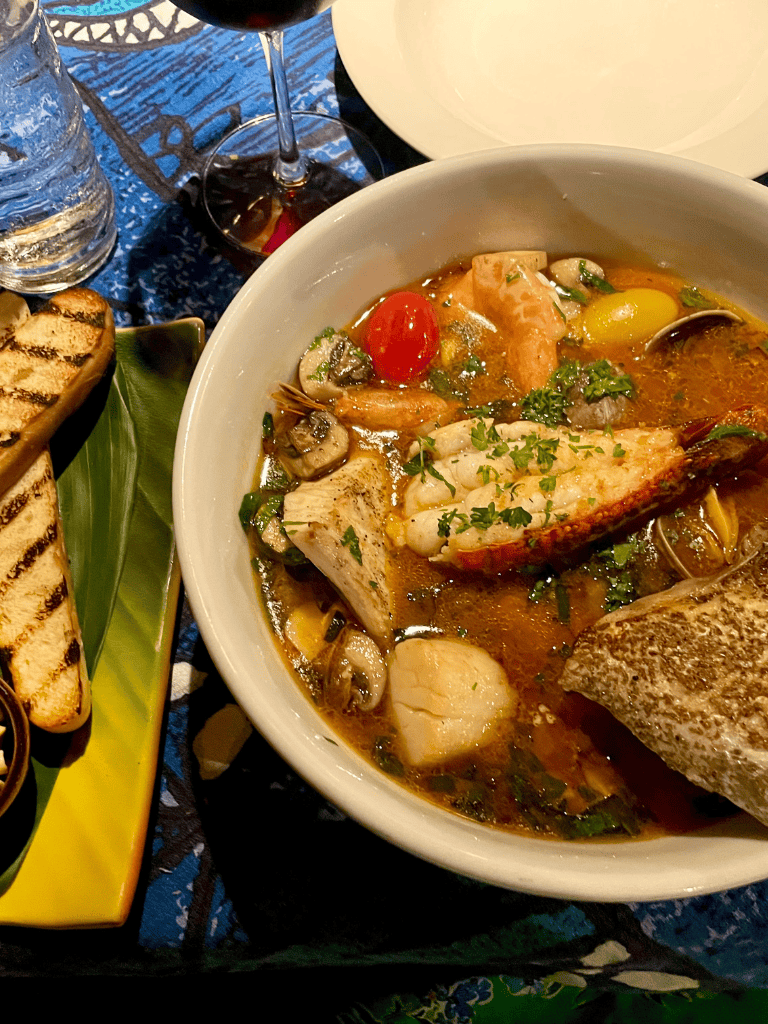 1. Fresh seafood soup with mushrooms, cherry tomatoes, and herbs in a white bowl.