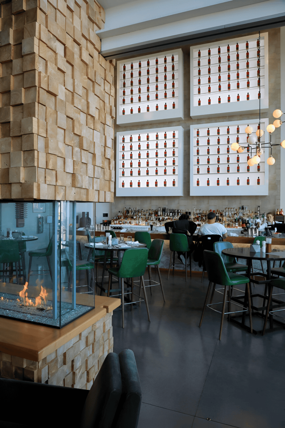 Modern stylish restaurant interior with wine bottle display and cozy seating area.