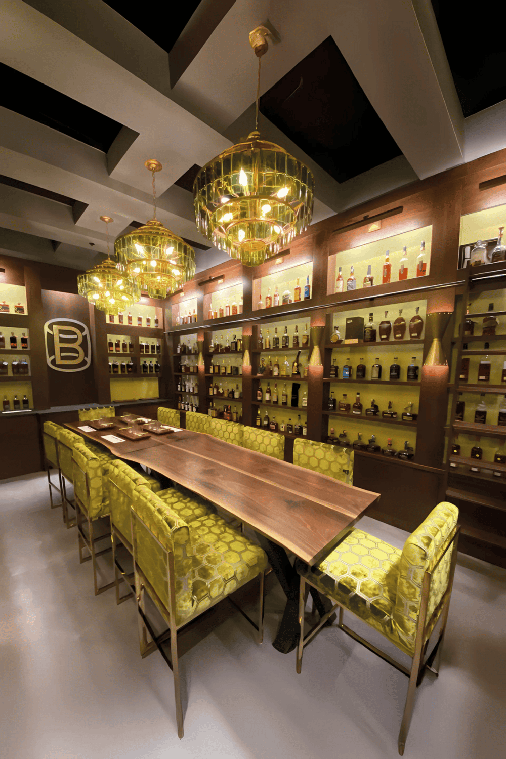 Luxurious bar or lounge with polished wooden table, gold chandeliers, and shelves of liquor bottles for upscale bar experiences.
