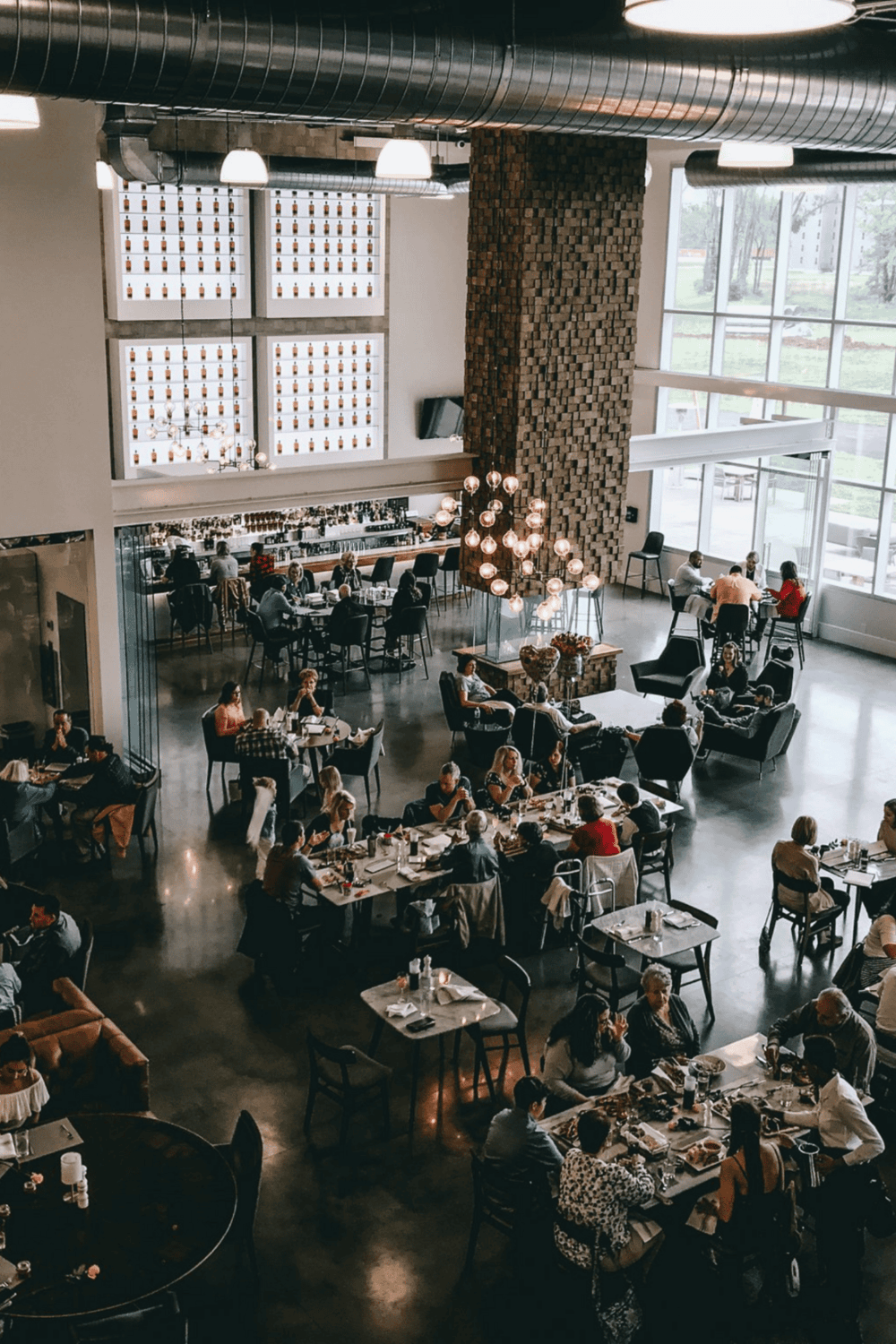 Cozy modern restaurant interior with large windows, stylish lighting, and diverse diners enjoying meals.