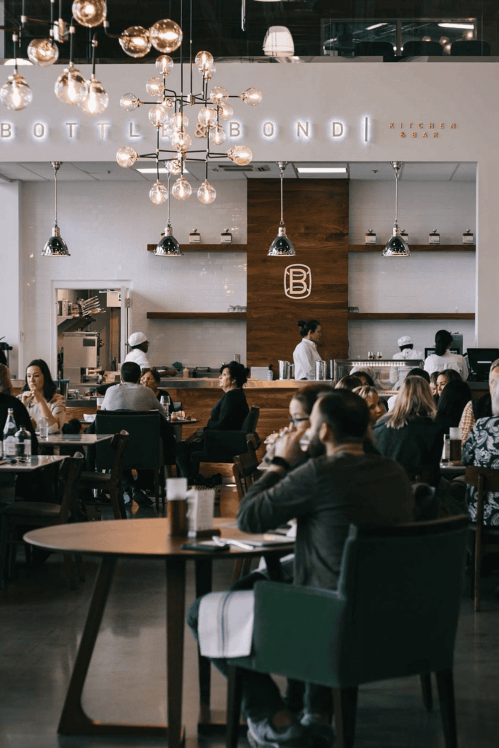 Modern brewery restaurant interior with patrons enjoying meals and drinks.