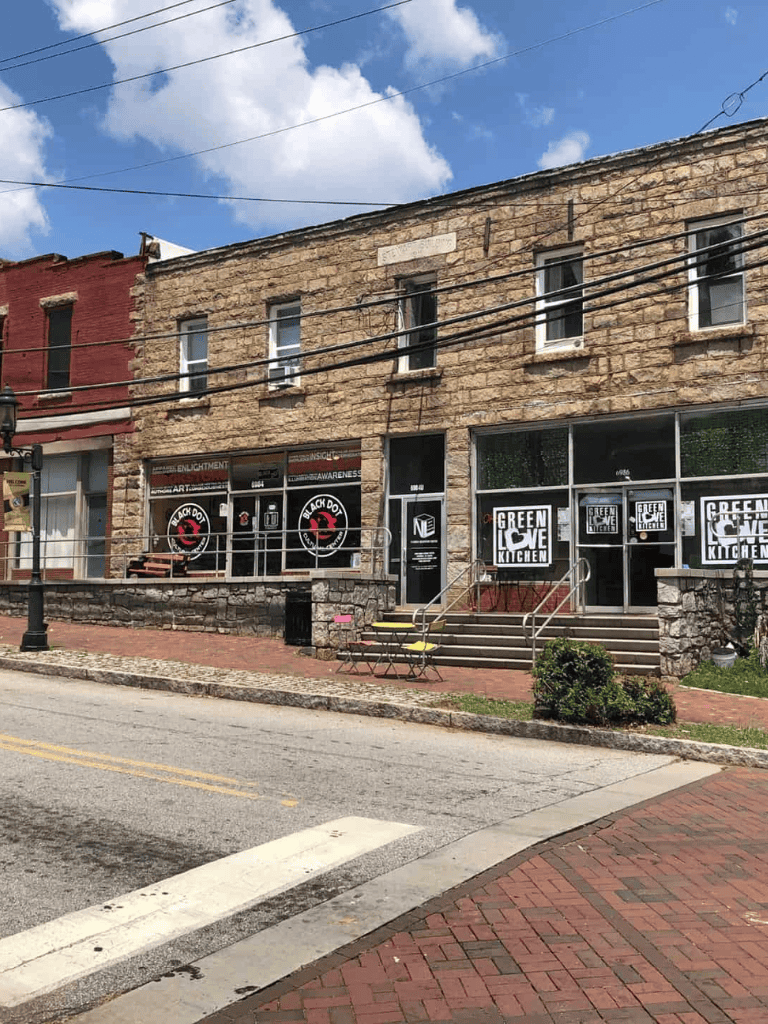 Vibrant storefront of Green Love Kitchen in a historic brick building, downtown street scene.