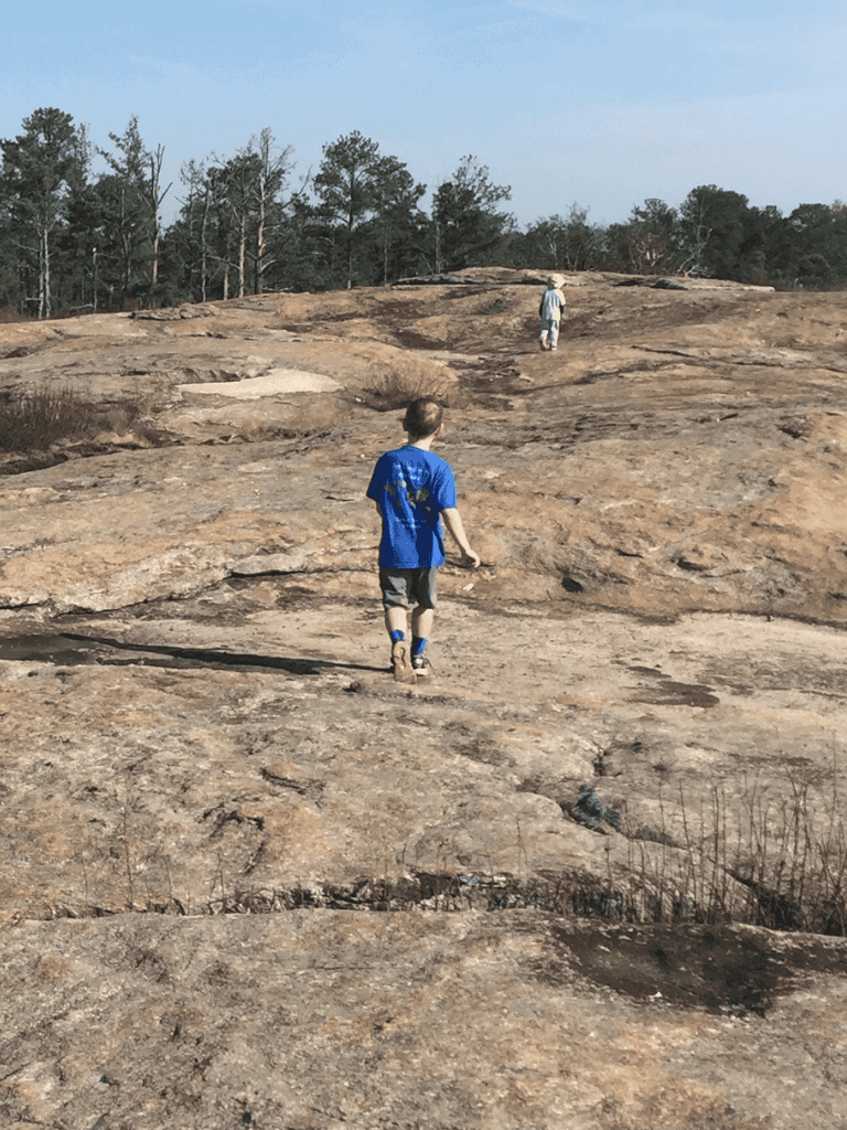 Child exploring rocky terrain in outdoor adventure.