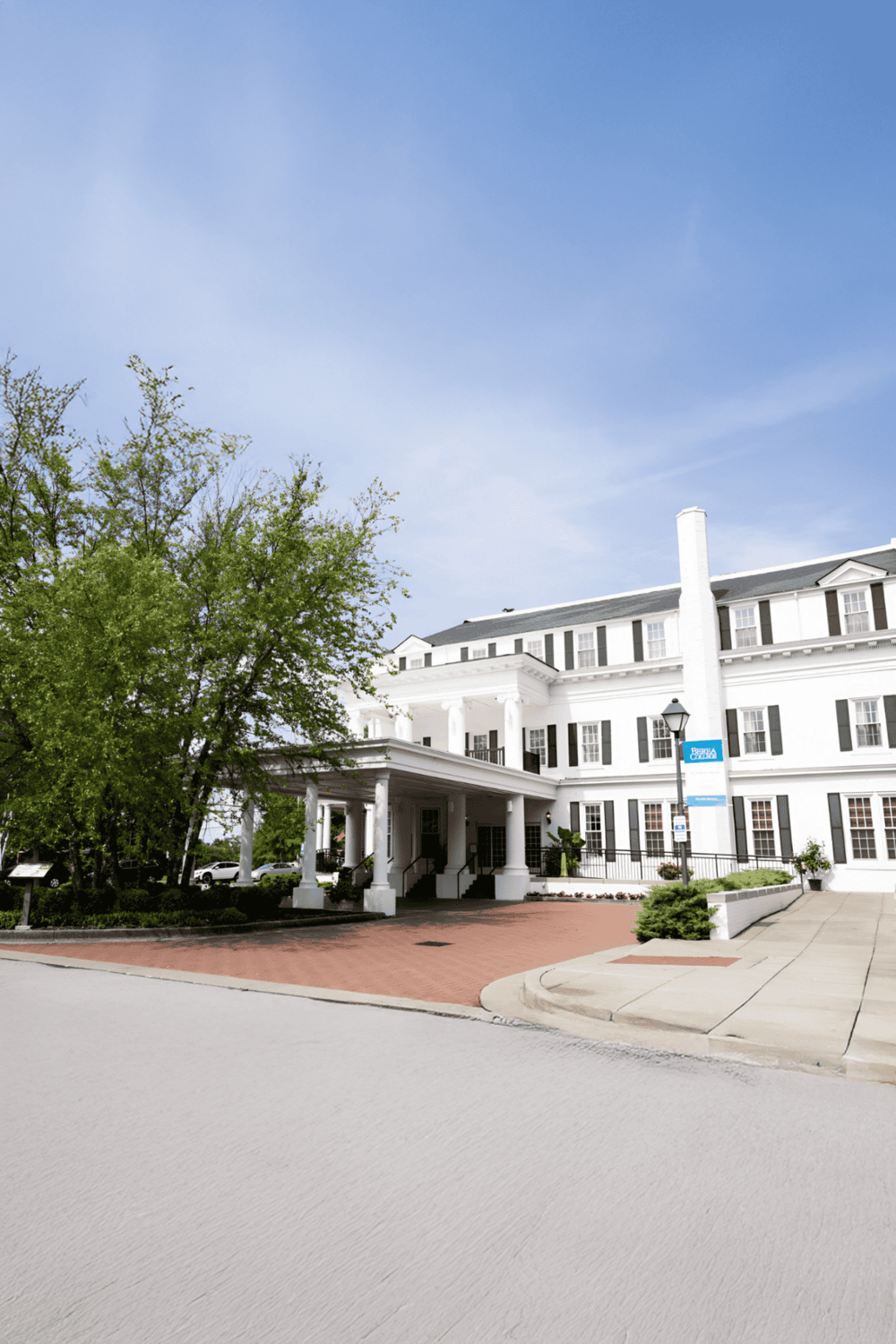 Elegant white hotel building with classic architecture and lush greenery in the surroundings.