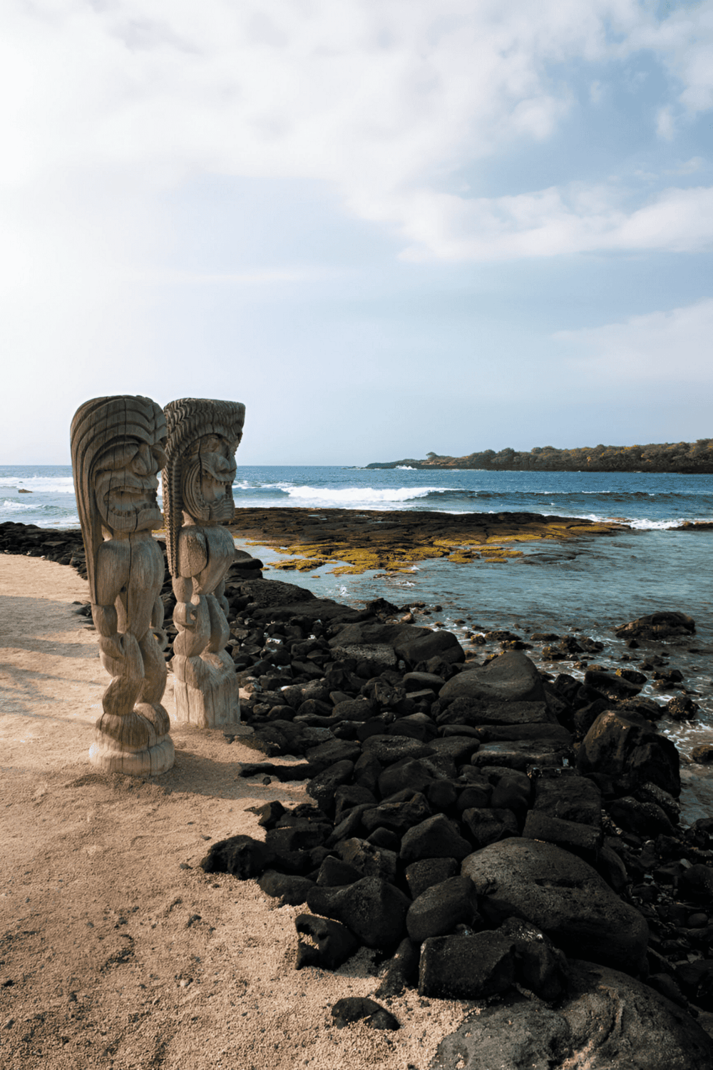 Carved Moai statues on a rocky beach with ocean view, Tahiti island travel destination.