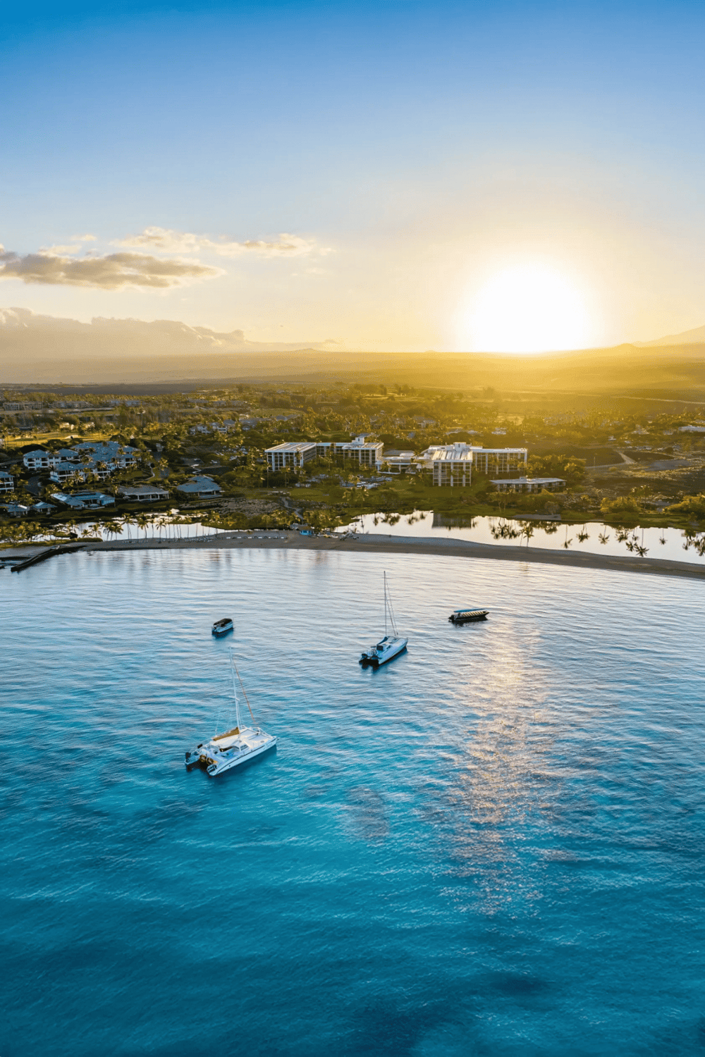 Sunset over a scenic coastal town with boats and luxurious buildings, showcasing paradise destinations.