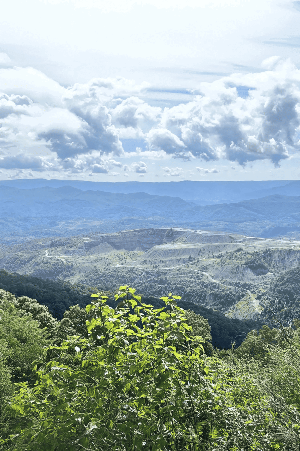 Cloud-covered mountain landscape with lush greenery and winding roads, perfect for outdoor adventures and scenic views.