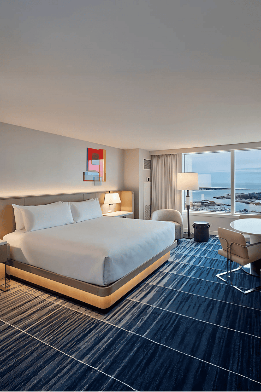 Modern hotel room with city and waterfront views, stylish decor, and comfortable amenities.
