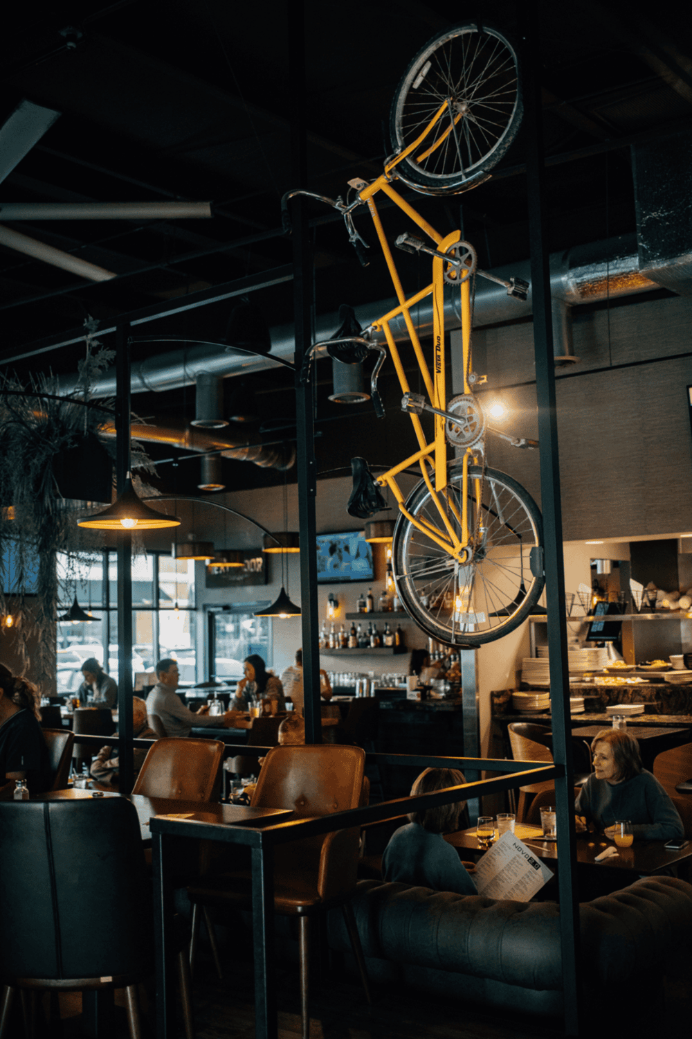 Bike sculpture hanging inside modern restaurant for unique decor.