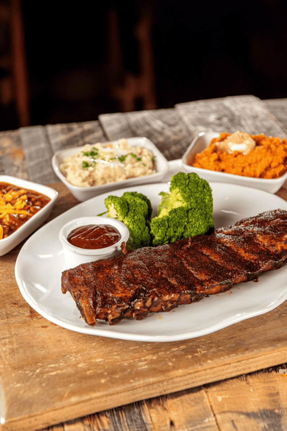Succulent BBQ ribs served with broccoli and flavorful side dishes in a cozy restaurant setting.