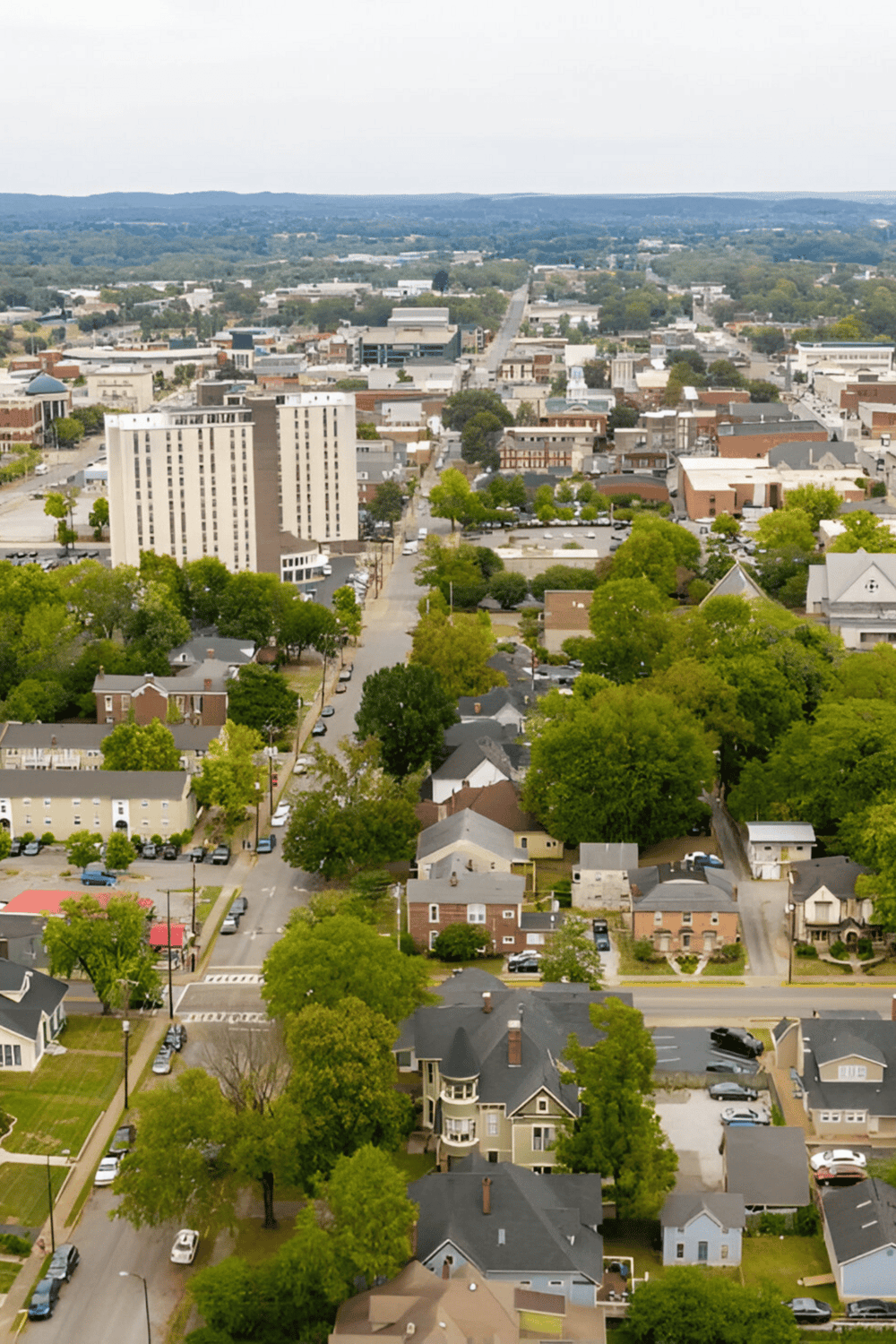 Aerial view of a cityscape showing buildings, trees, and streets in a scenic downtown area.