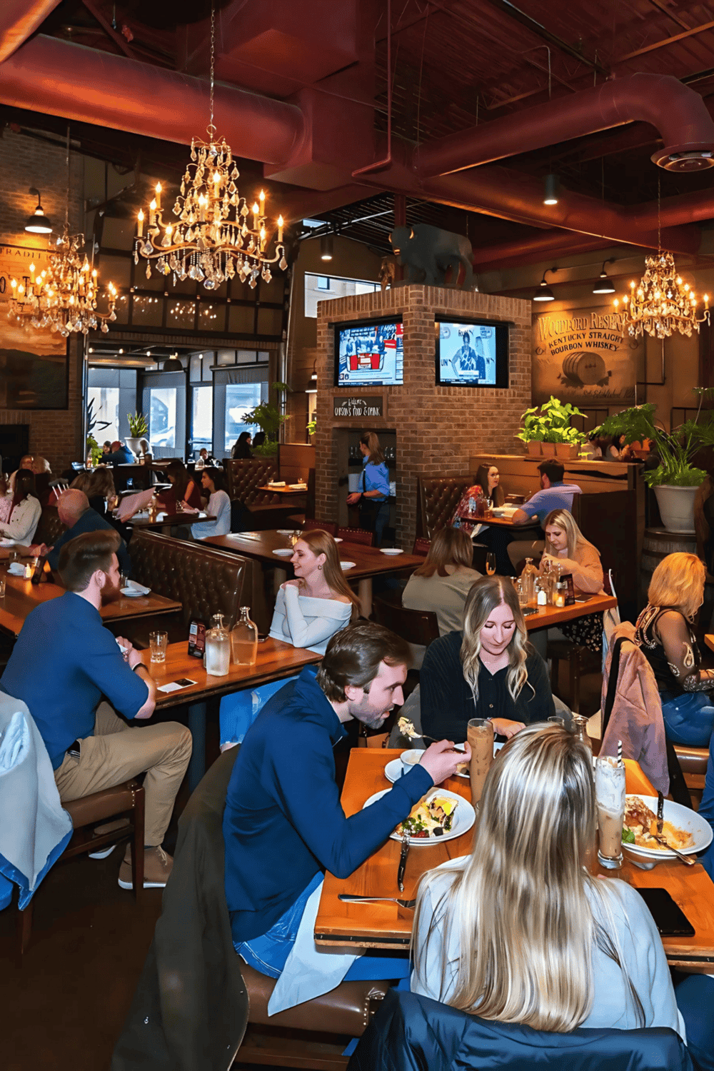 Cozy restaurant with elegant chandeliers, brick accents, and vibrant atmosphere, ideal for socializing and dining.