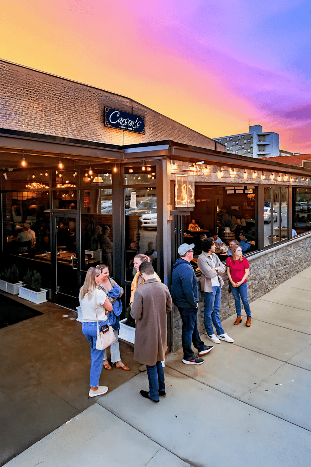 Charming restaurant exterior at sunset with people waiting, featuring QuestForDirections branding.