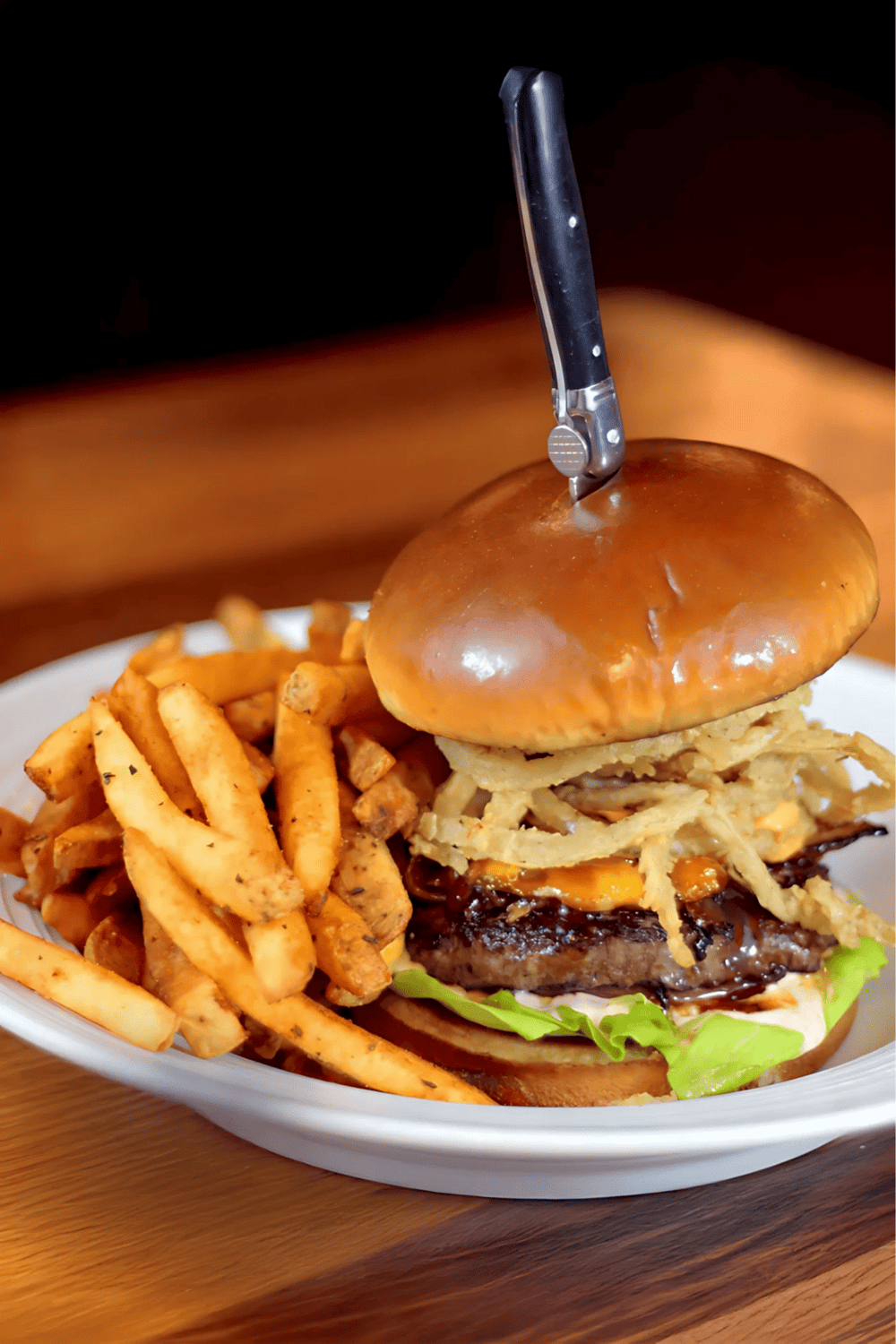 Savory cheeseburger with crispy fries, served on a white plate, perfect for comfort food lovers.