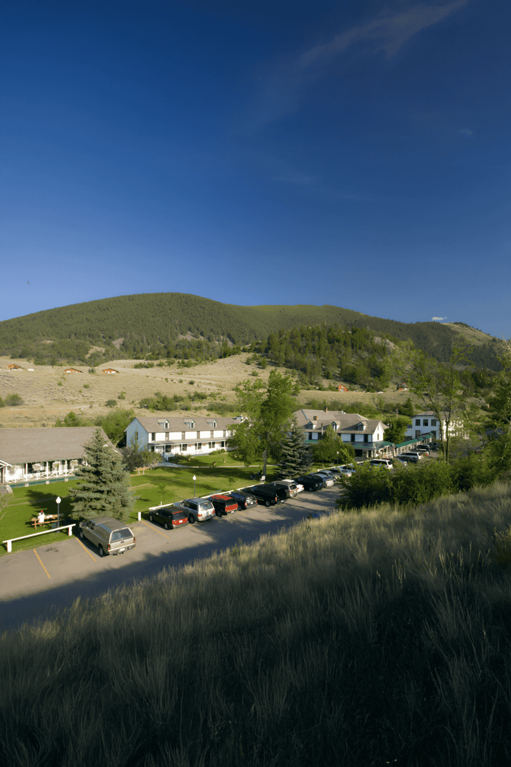 Scenic mountain hotel with furnished rooms and parking, surrounded by lush greenery, perfect for outdoor adventures.