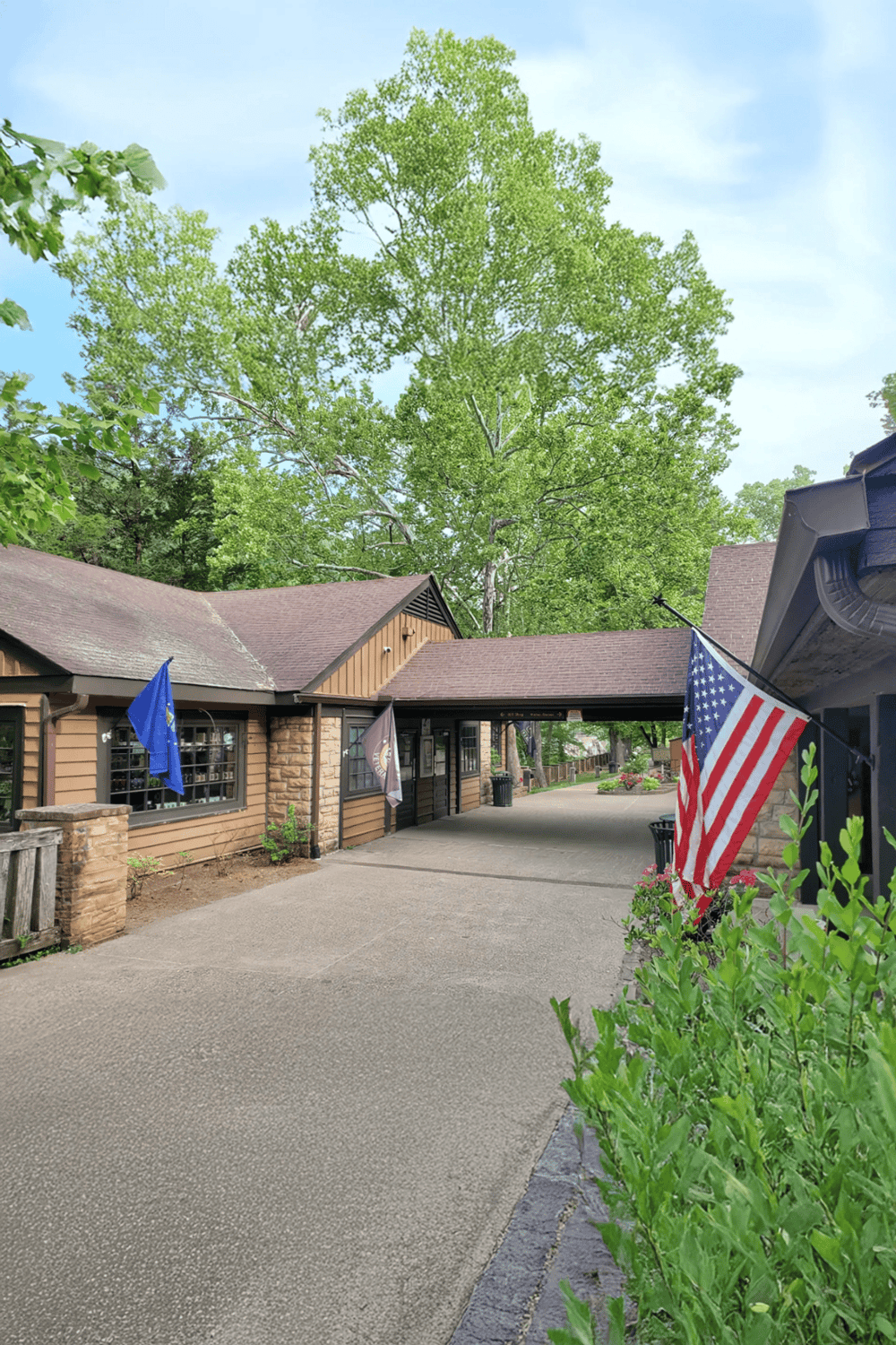 Old-fashioned American roadside restaurant with flags, trees, and rustic building exterior.