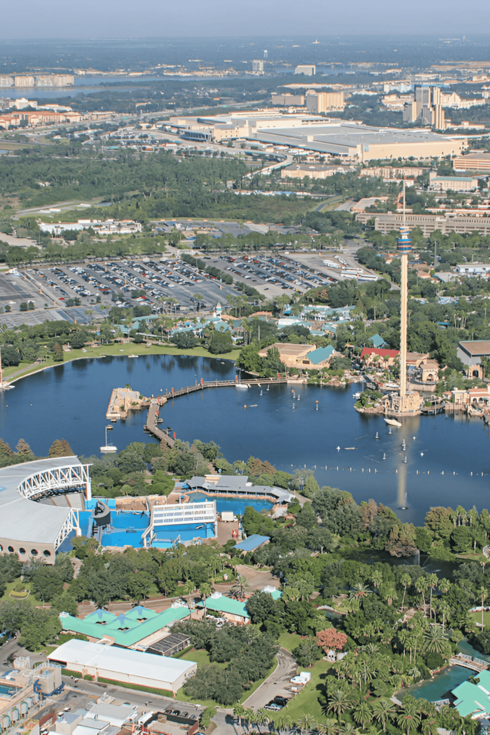 Aerial view of Quest for Directions theme park with lake, rides, and city skyline in the background.