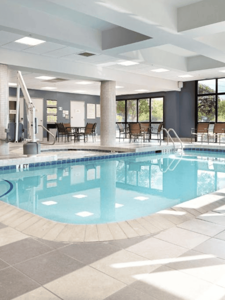 Indoor swimming pool at QuestForDirections hotel with large windows and seating area.