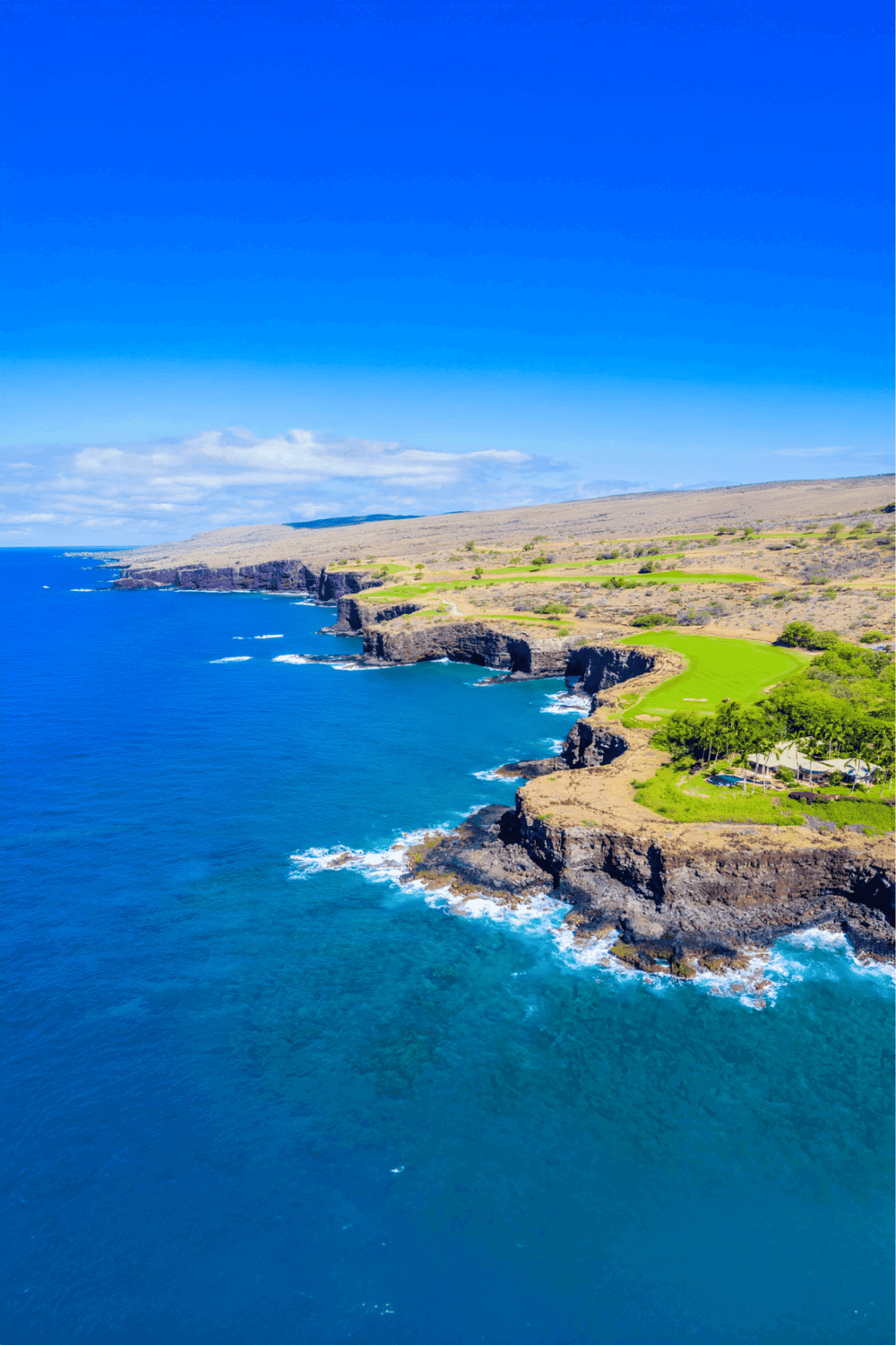 Stunning aerial view of coastal cliffs and golf course on Hawaii island.