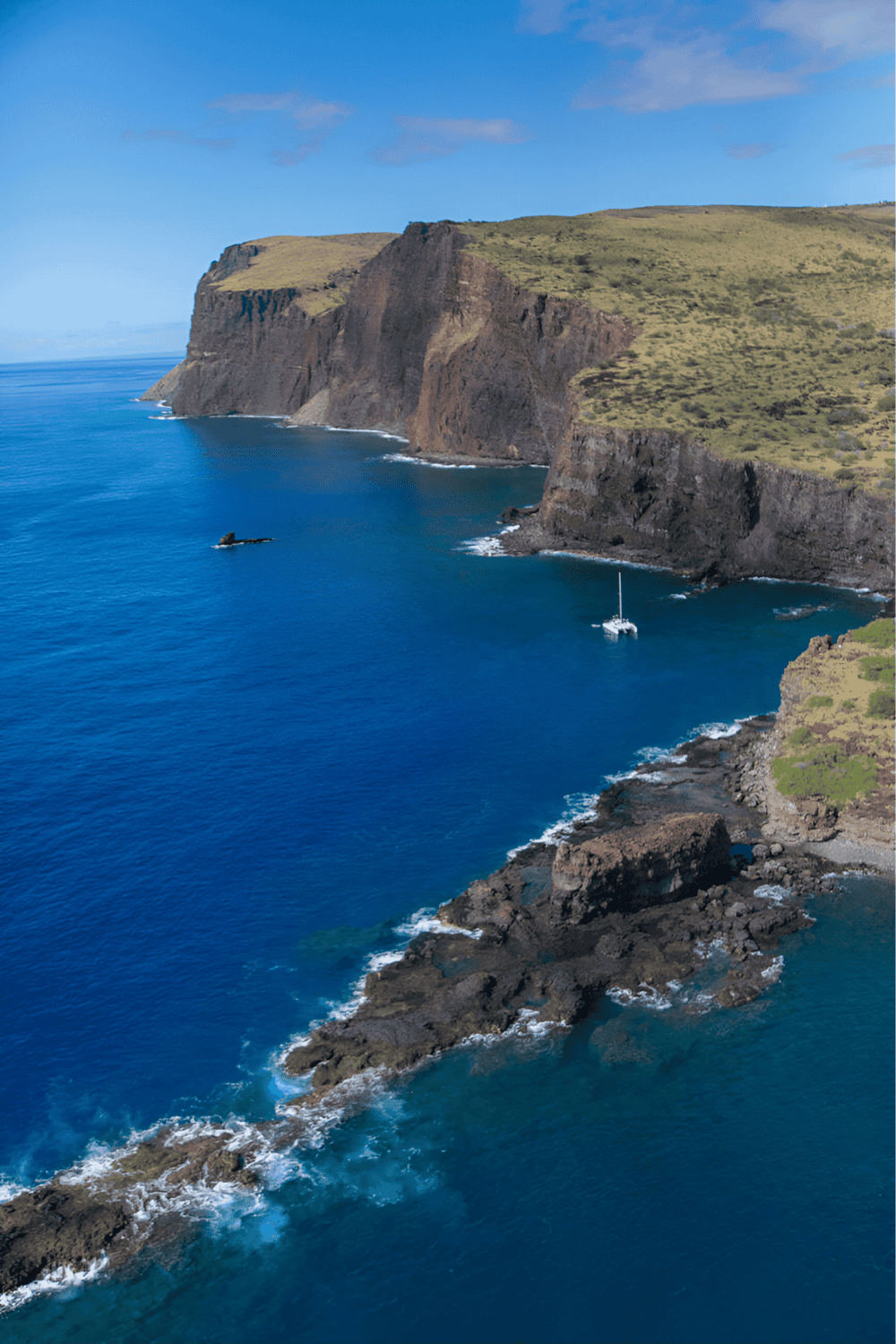 Cliffs along the ocean coast with boats, scenic views, and lush green landscape.