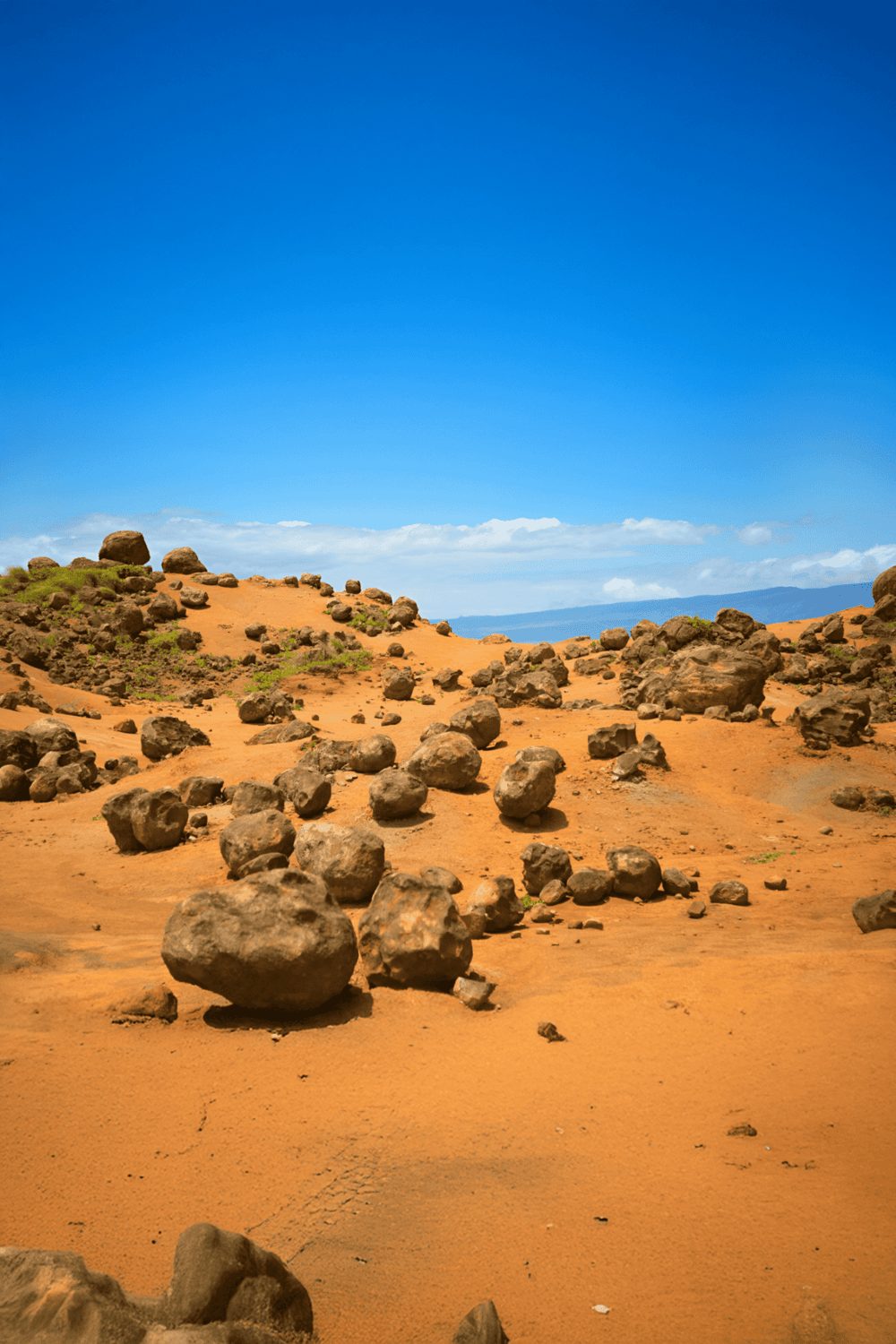 Arid desert landscape with scattered rocks under clear blue sky, perfect for outdoor adventures and travel planning.