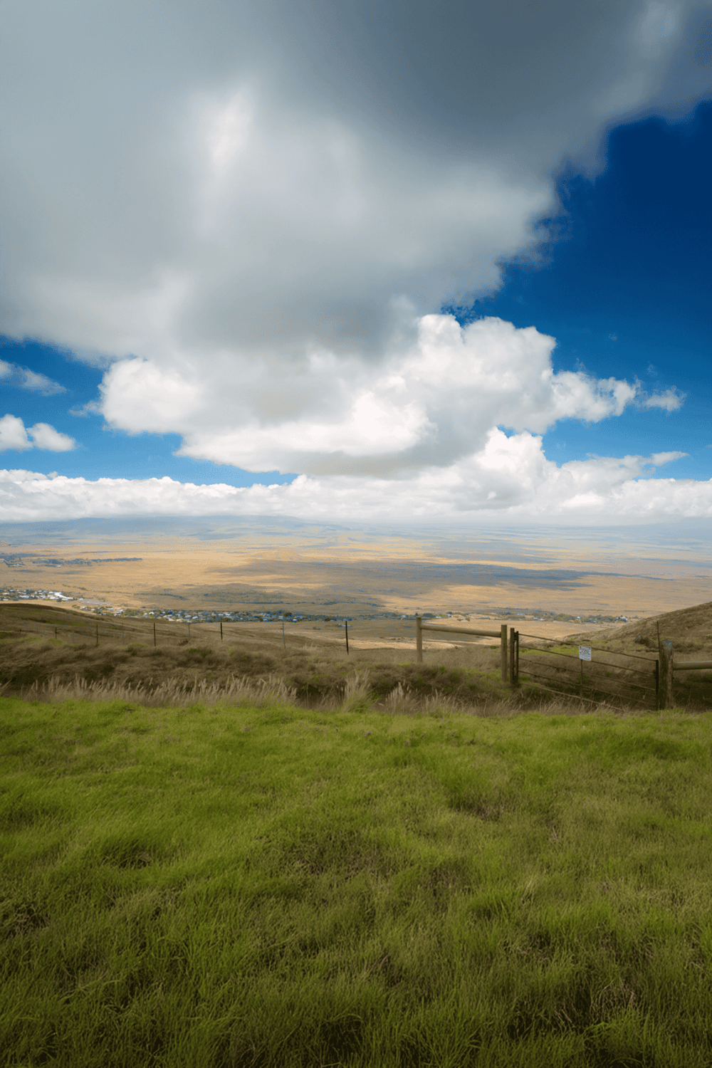 Vast open landscape with grassy foreground, rolling hills, and dramatic cloudy sky, ideal for outdoor adventure and nature exploration.