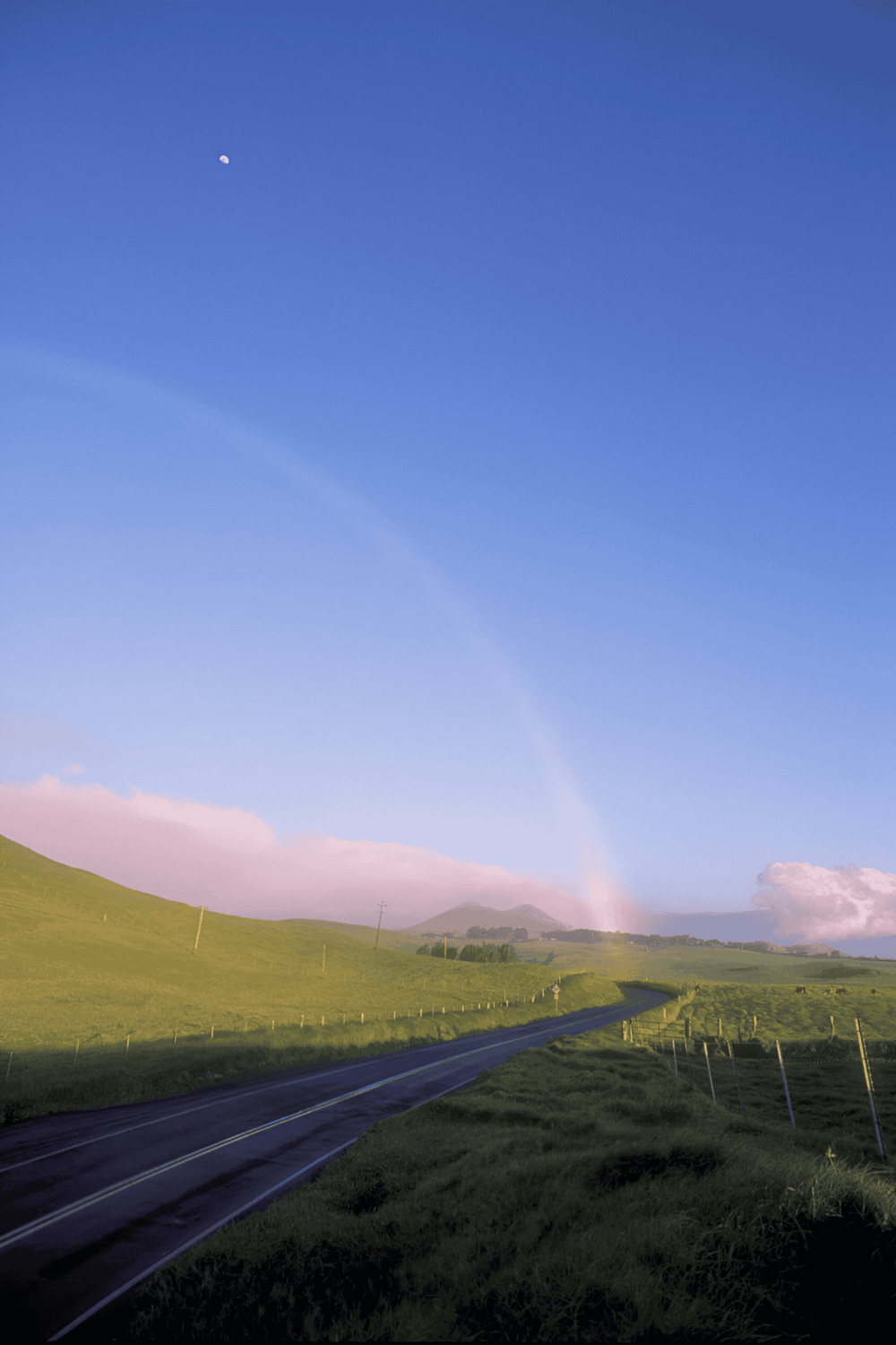 Aerial view of scenic rural highway with rainbow and blue sky, beautiful landscape, travel, directions, navigation.