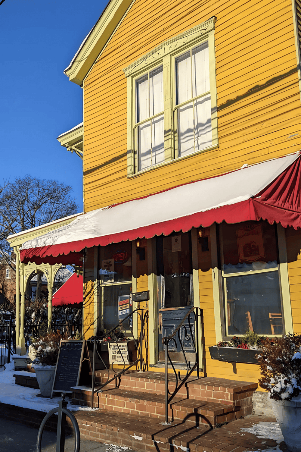 Cozy yellow historic building with a restaurant featuring a red and white awning in a charming neighborhood.