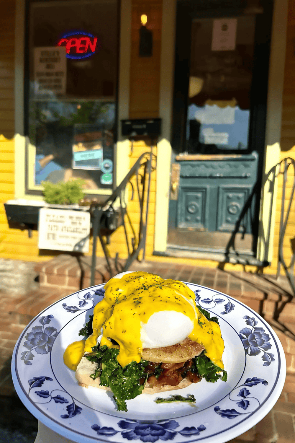 Eggs Benedict with hollandaise sauce served outside a cozy restaurant.