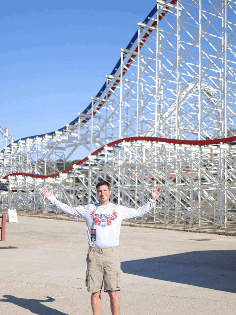Roller coaster at QuestForDirections amusement park with smiling staff member.