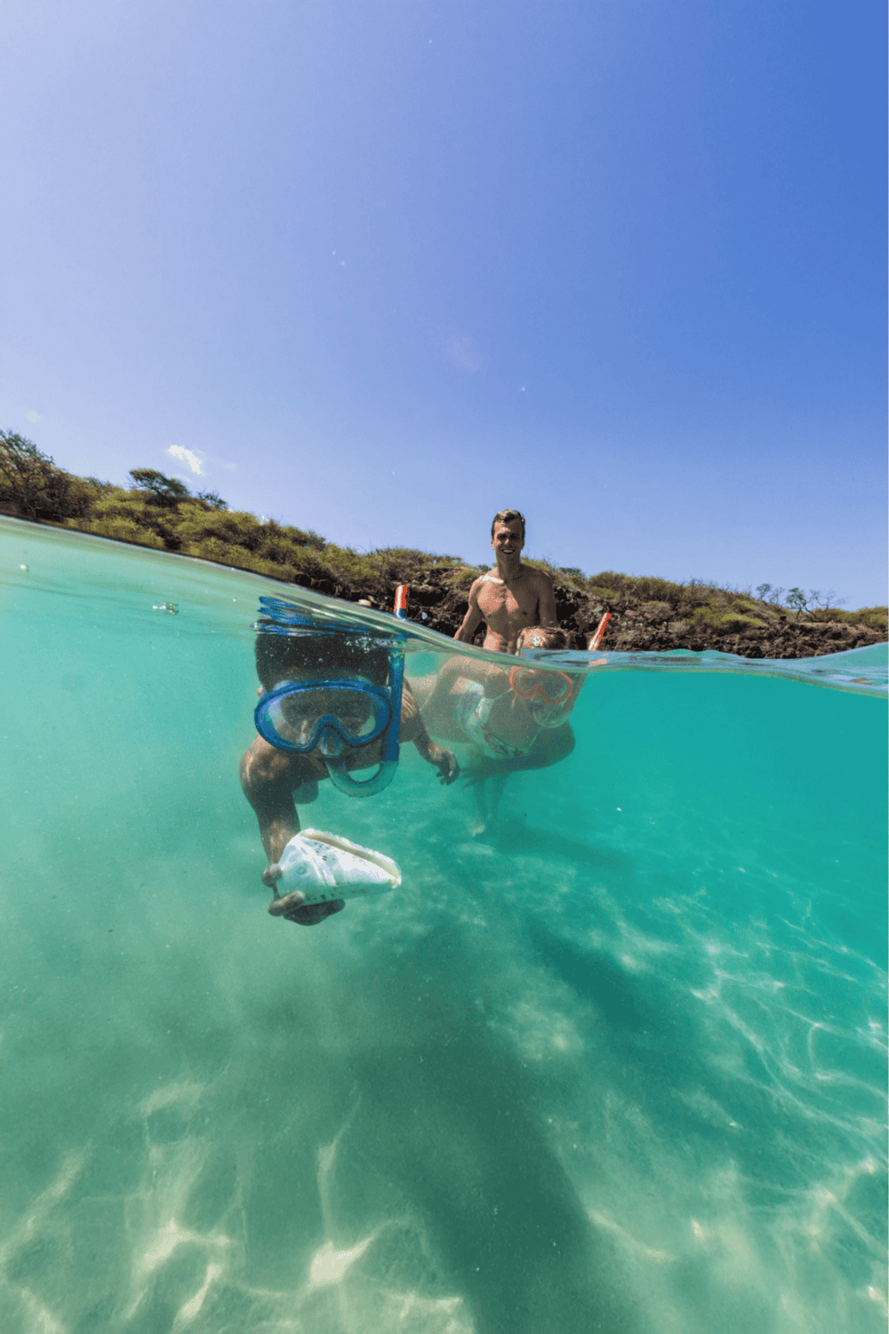 Overwater snorkeling with two people in clear turquoise water on a sunny day.