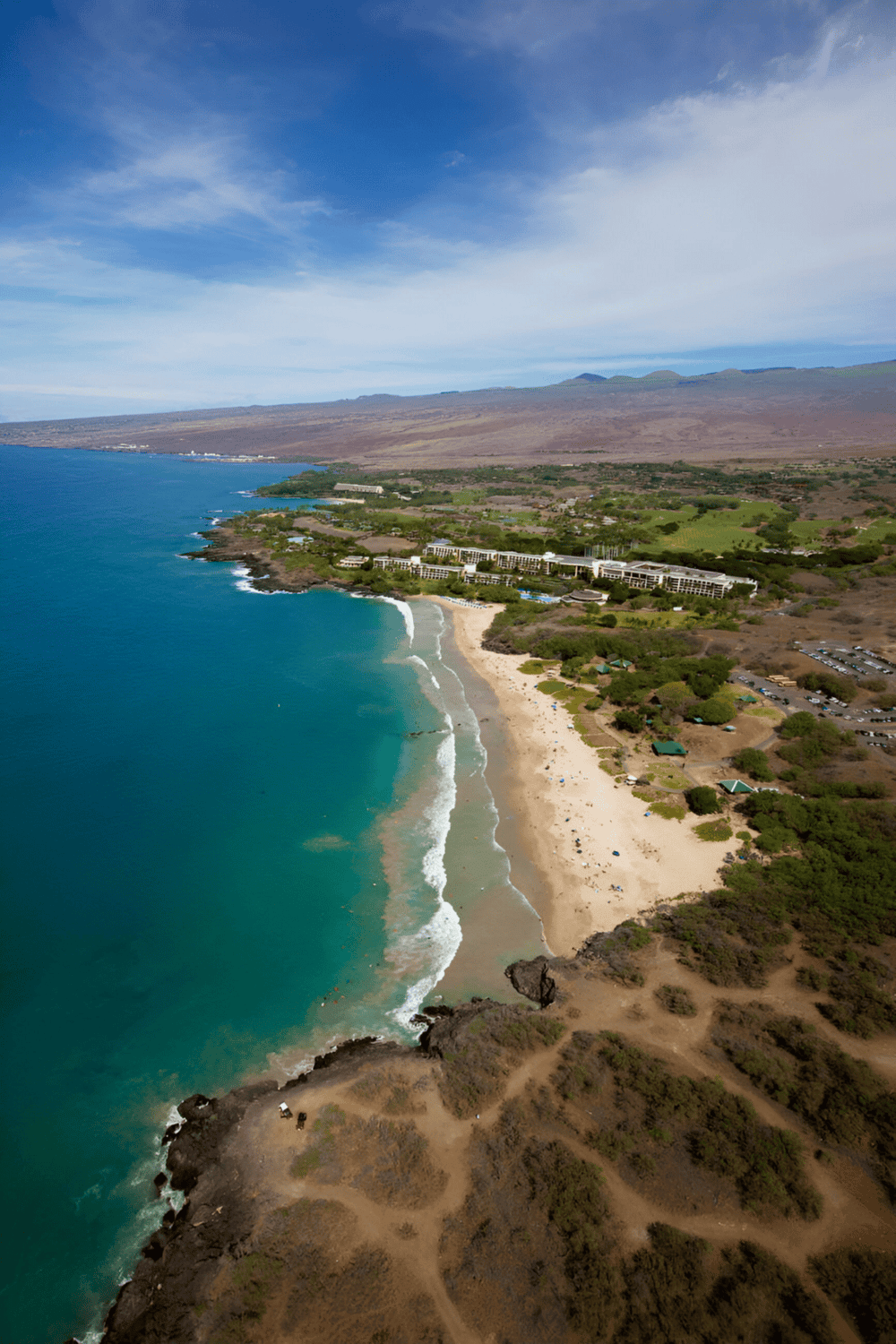 Cliffs surrounding a scenic Hawaiian beach with turquoise waters and lush greenery, ideal for exploring with Quest For Directions.