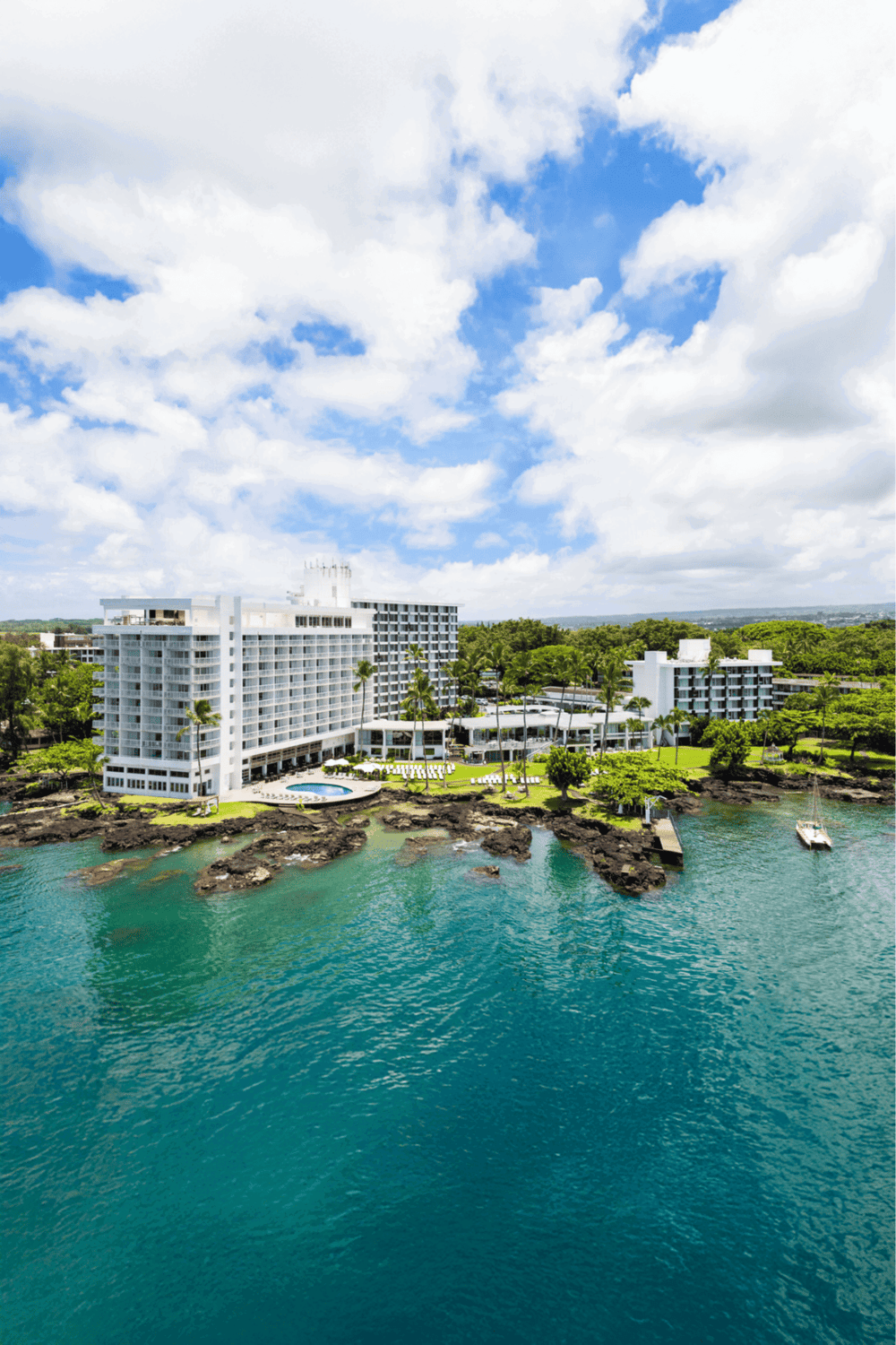 Luxury beachfront hotel with stunning ocean views and tropical landscape, perfect for vacation or getaway.