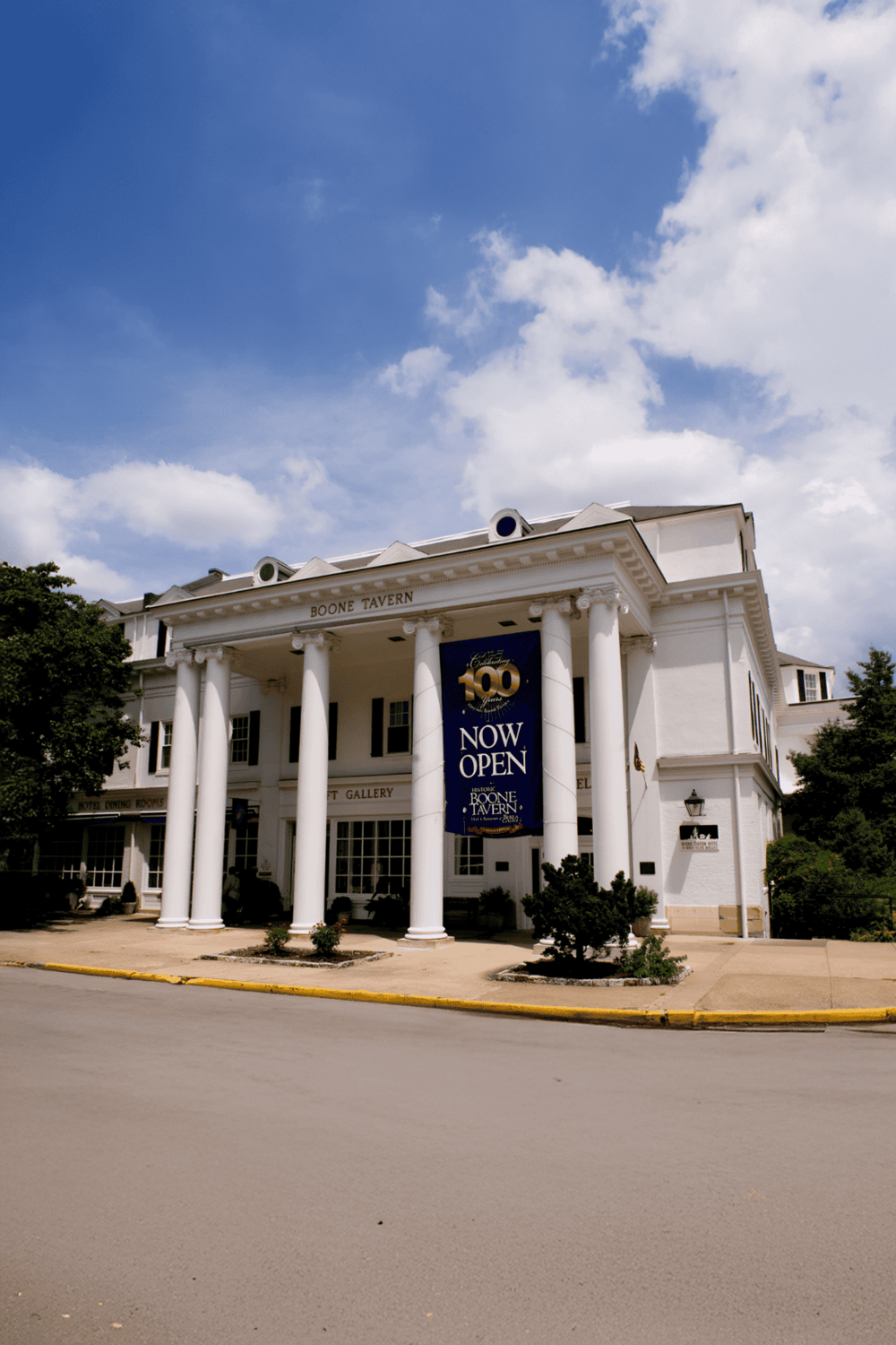 Vintage brick building with large white columns, now open for visitors at Boone Tavern, perfect for historical exploration.