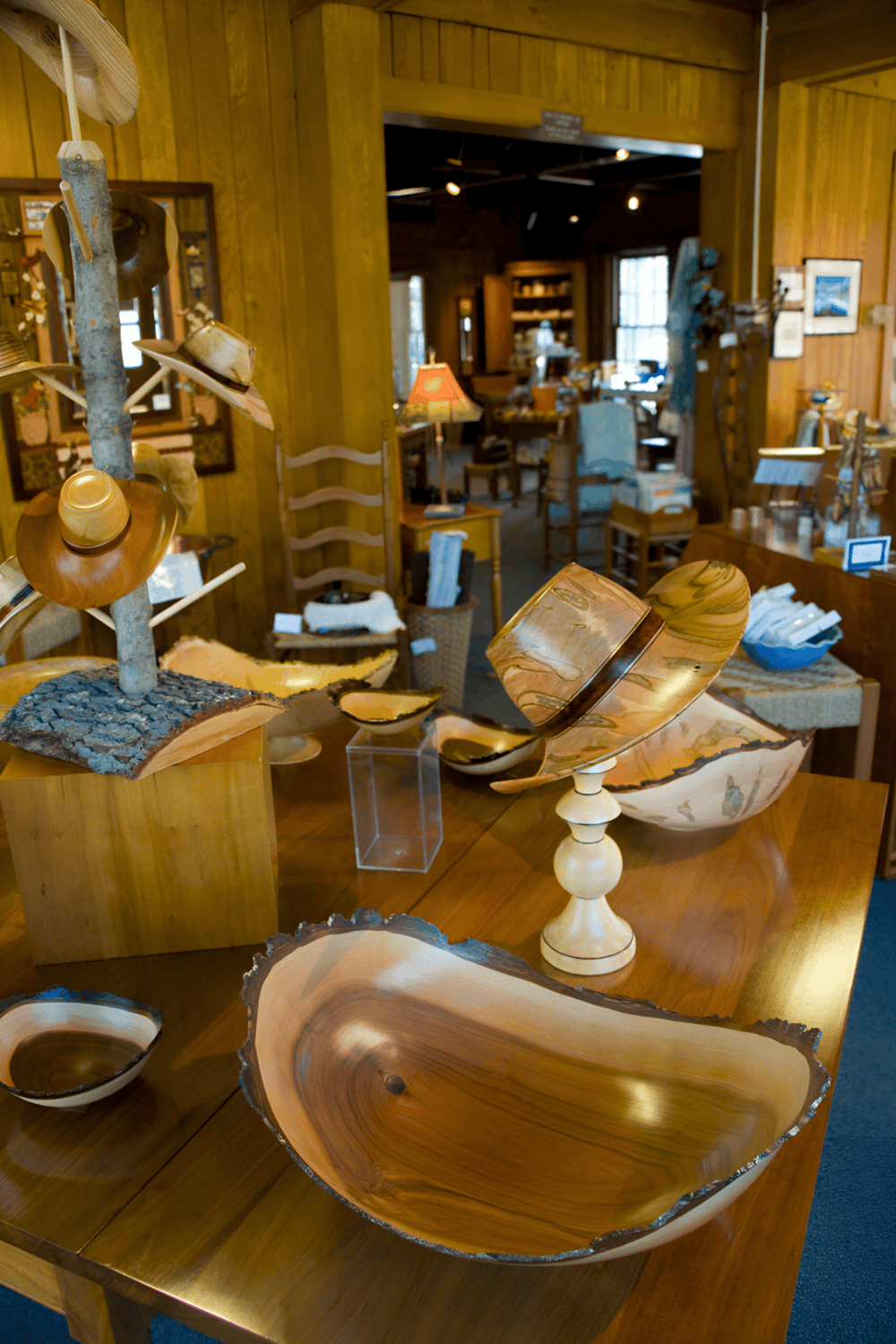 Handcrafted wooden bowls and art pieces inside a cozy wood interior gift shop.