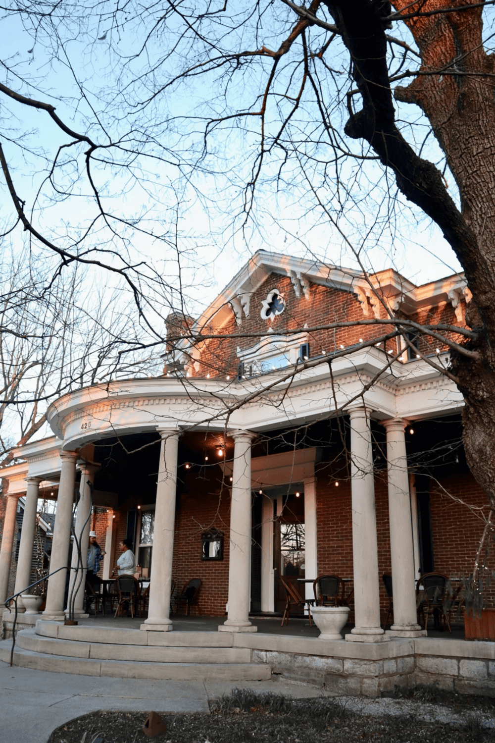 Charming historic brick house with a large porch and elegant columns, ideal for residential or commercial use.