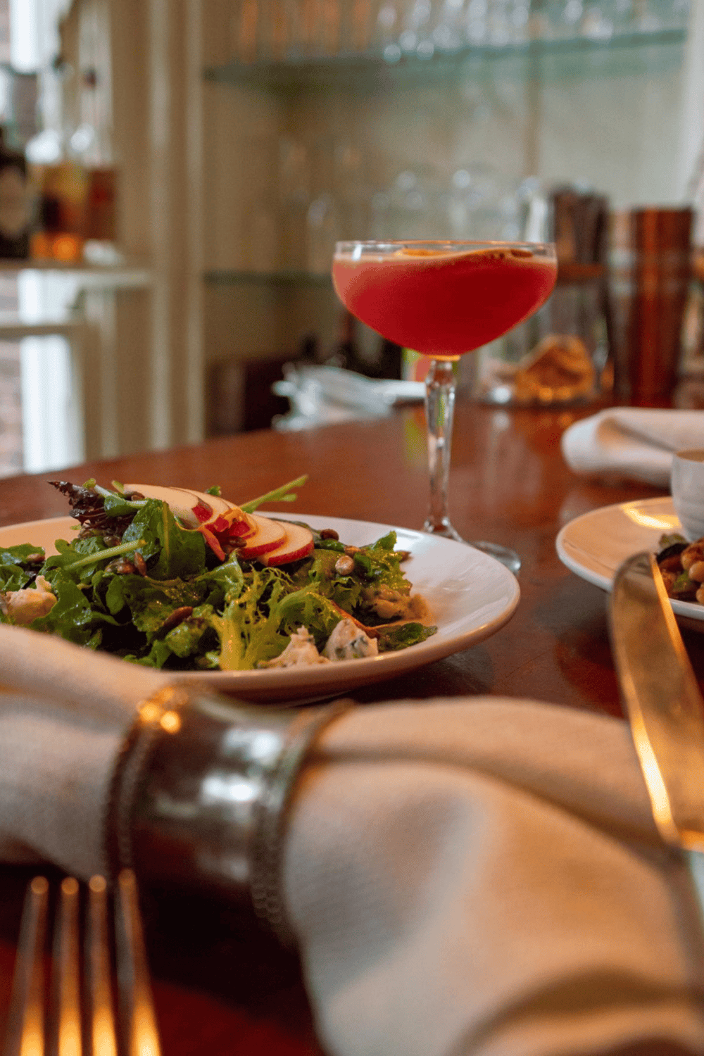 Elegant cocktail and fresh salad at upscale restaurant for fine dining experience.